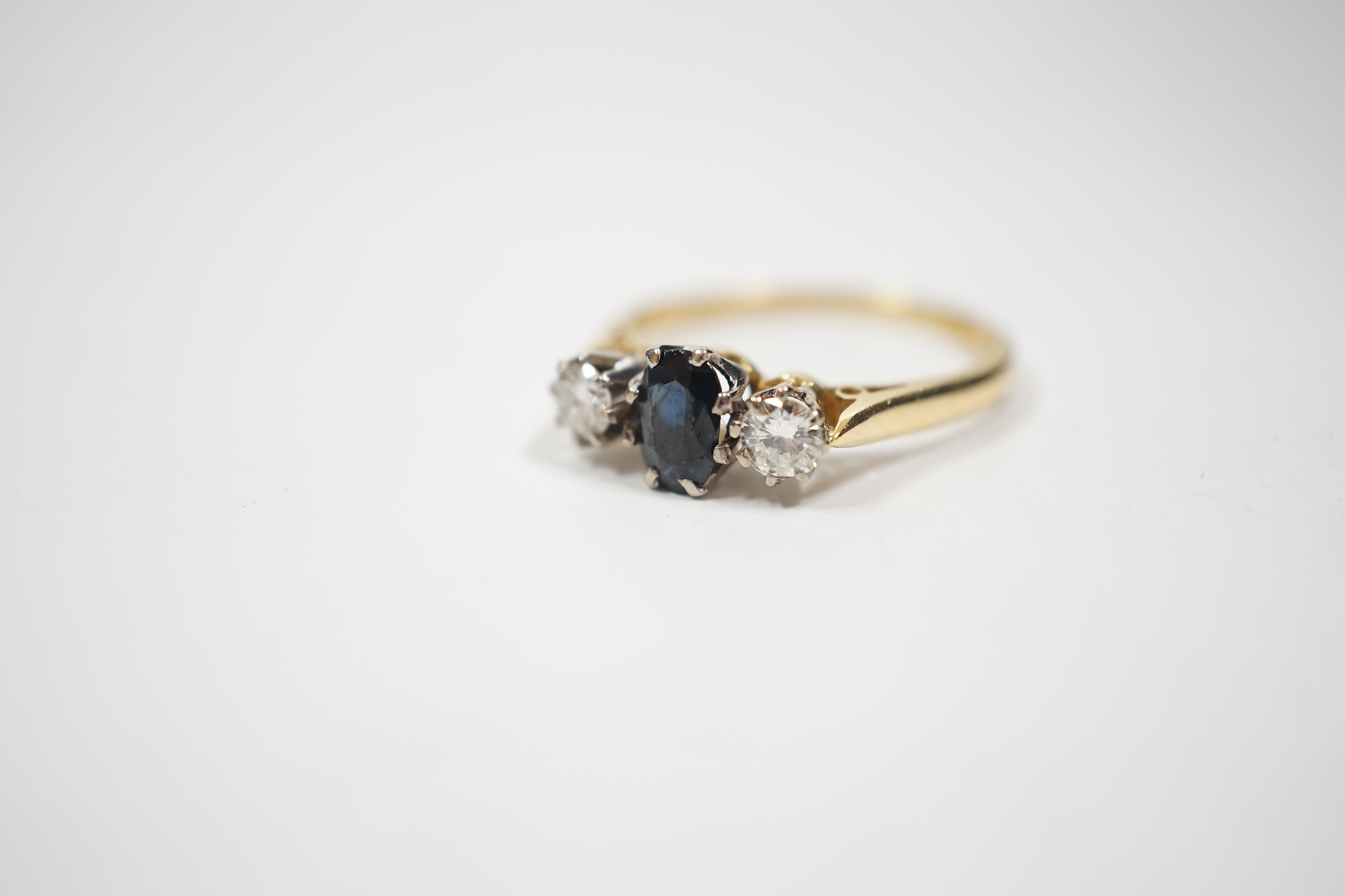 An 18ct, sapphire and diamond set three stone ring, size N, gross weight 2.8 grams.